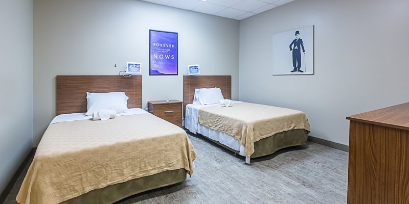 A clean and cozy bedroom with two neatly made beds, soft lighting, and simple decor, providing a comfortable and restful environment.