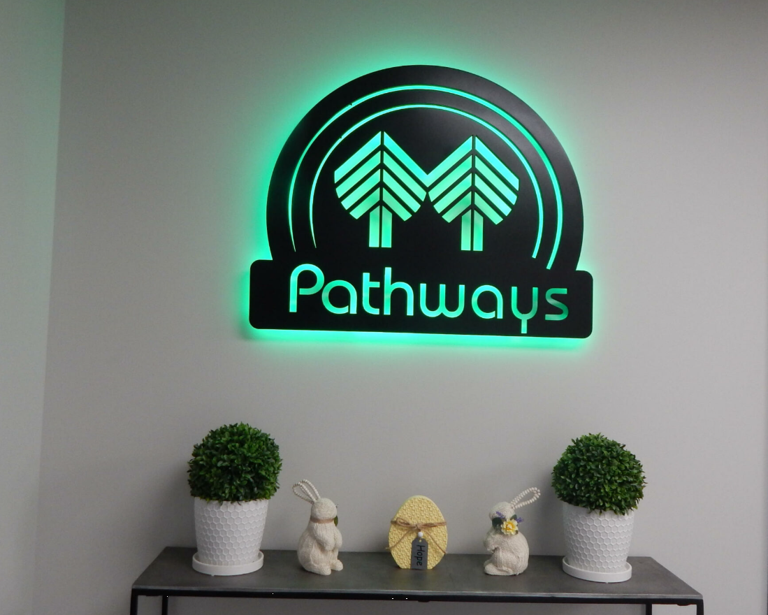 Illuminated Pathways logo displayed on an interior wall with decor