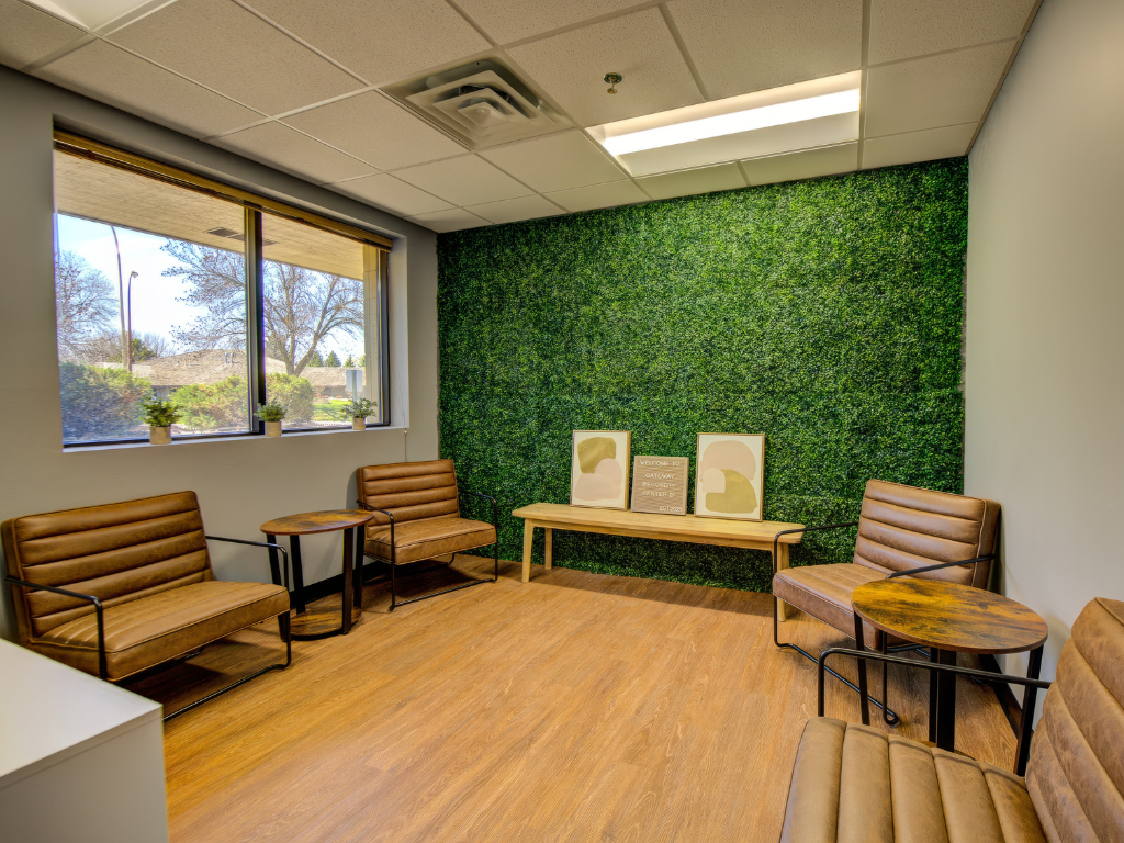Small seating area with brown chairs and green plant wall