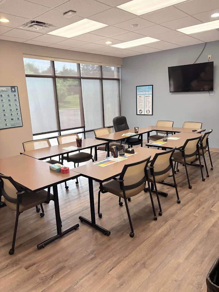 Group therapy room with tables, chairs, and television