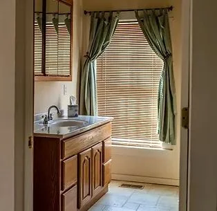 Clean shared bathroom with sink, mirror, and natural light