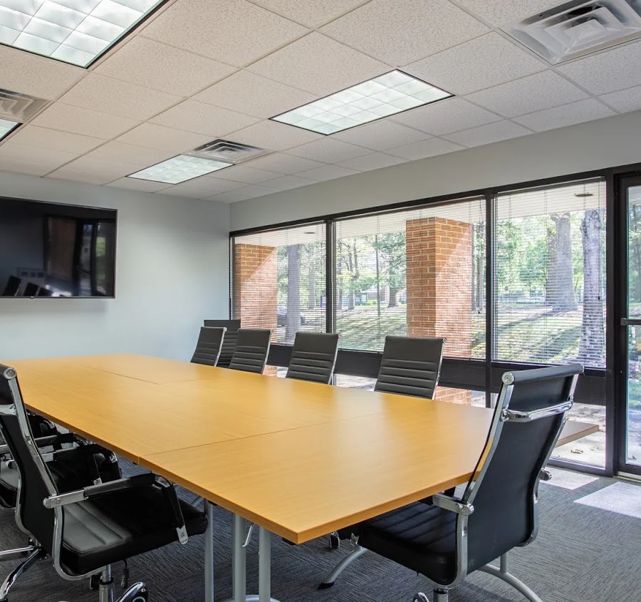 Meeting room with large table, black chairs, and windows