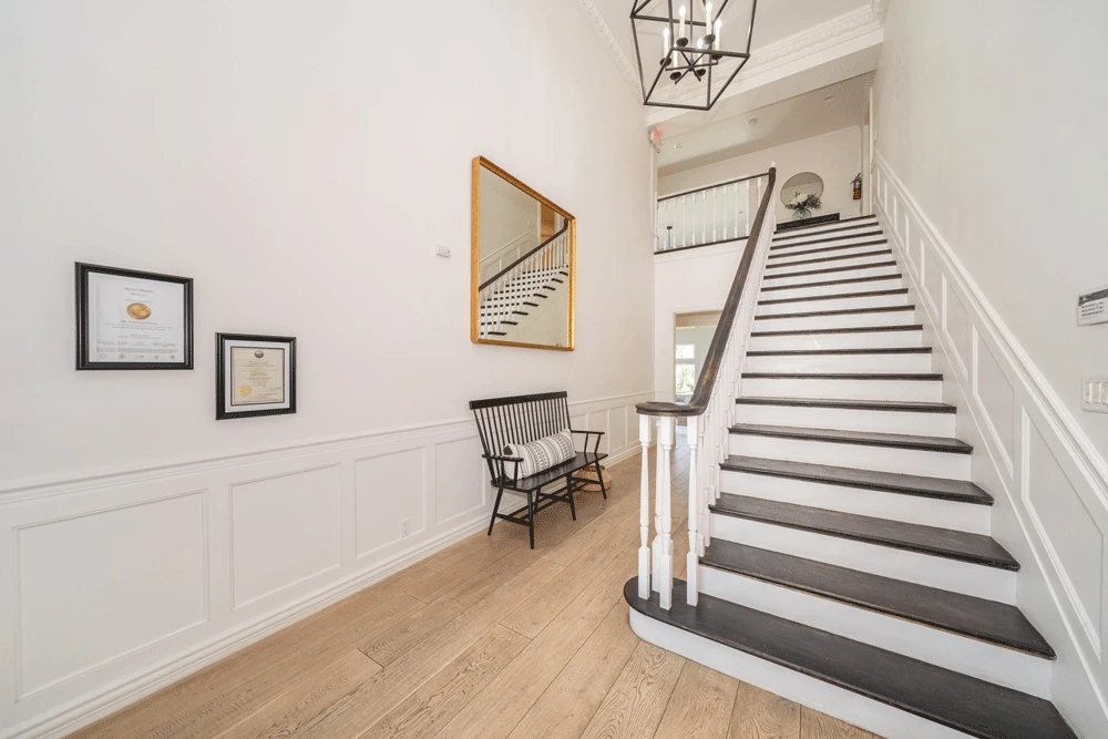 Grand staircase with wooden bench and wall decor