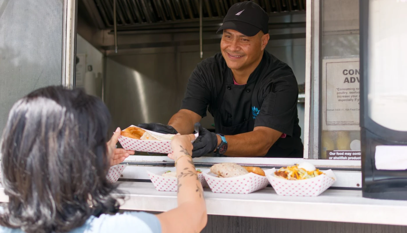 Chef handing a meal to a guest from a food service window