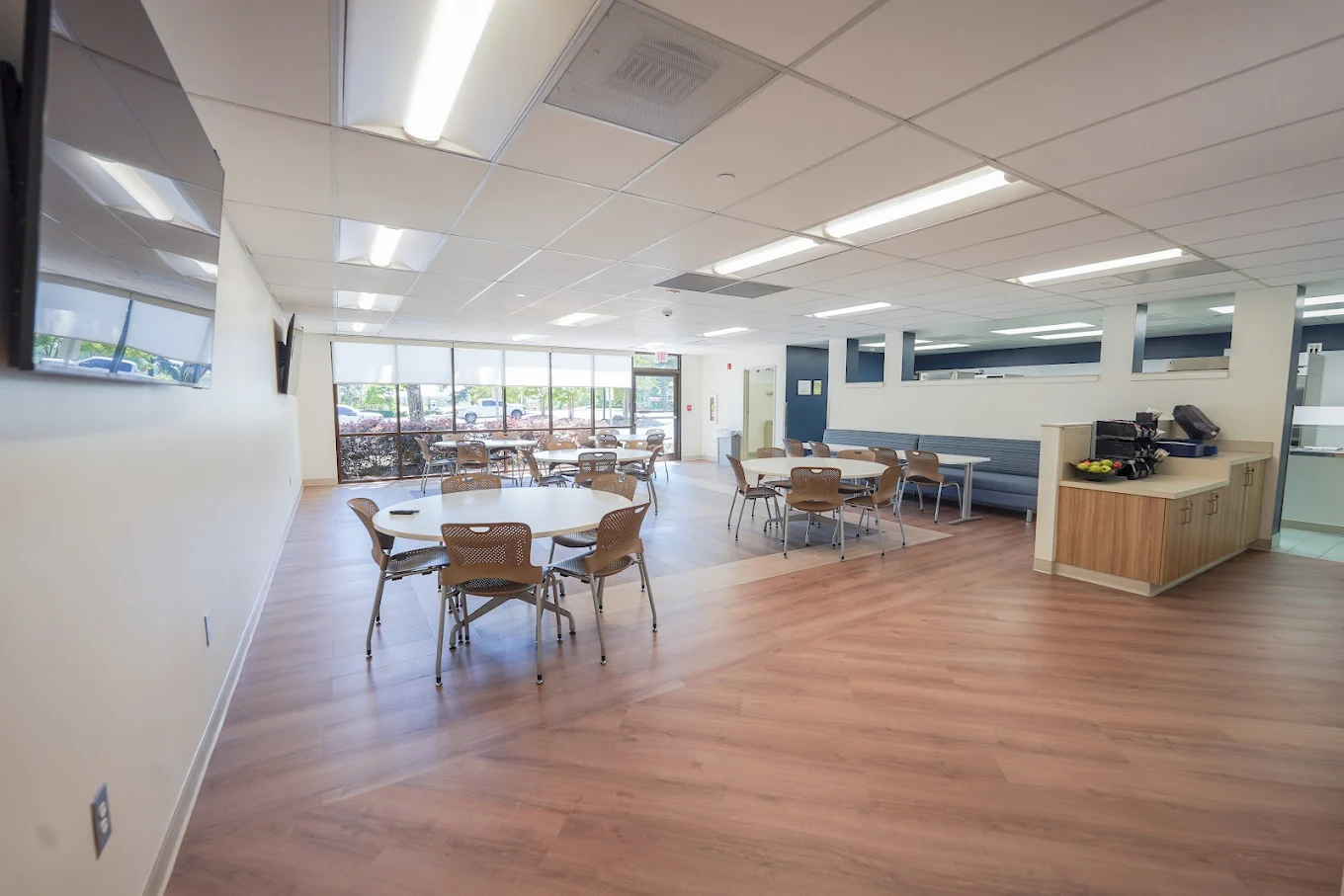Community lounge with tables, chairs, and large windows
