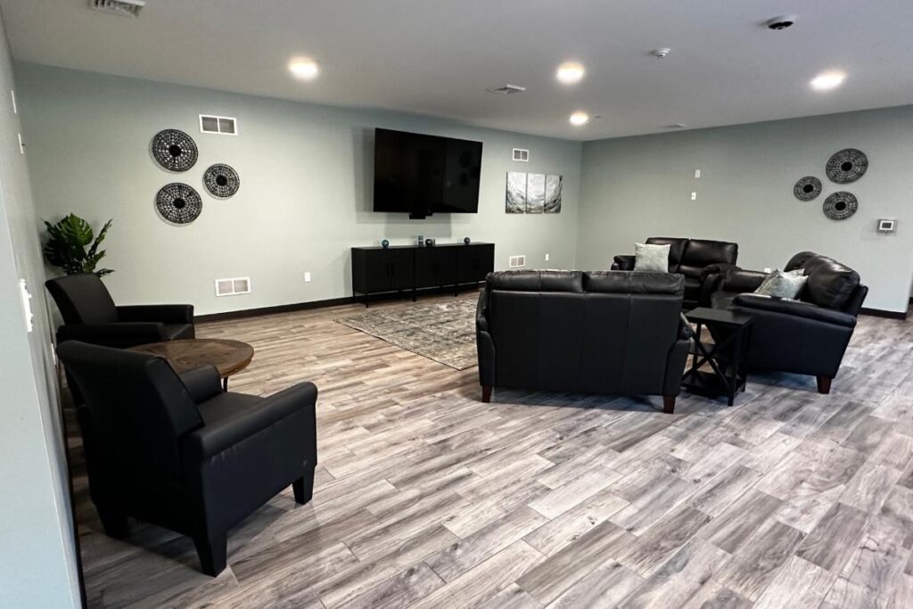 Black leather sofas facing mounted TV in modern lounge