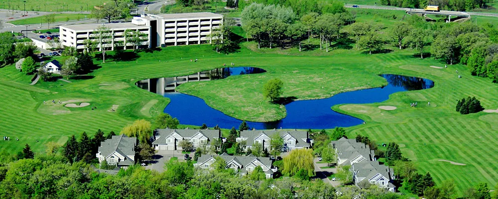 Aerial view of the Hazelden Betty Ford Foundation facility in Chaska surrounded by a golf course, ponds, trees, and residential buildings