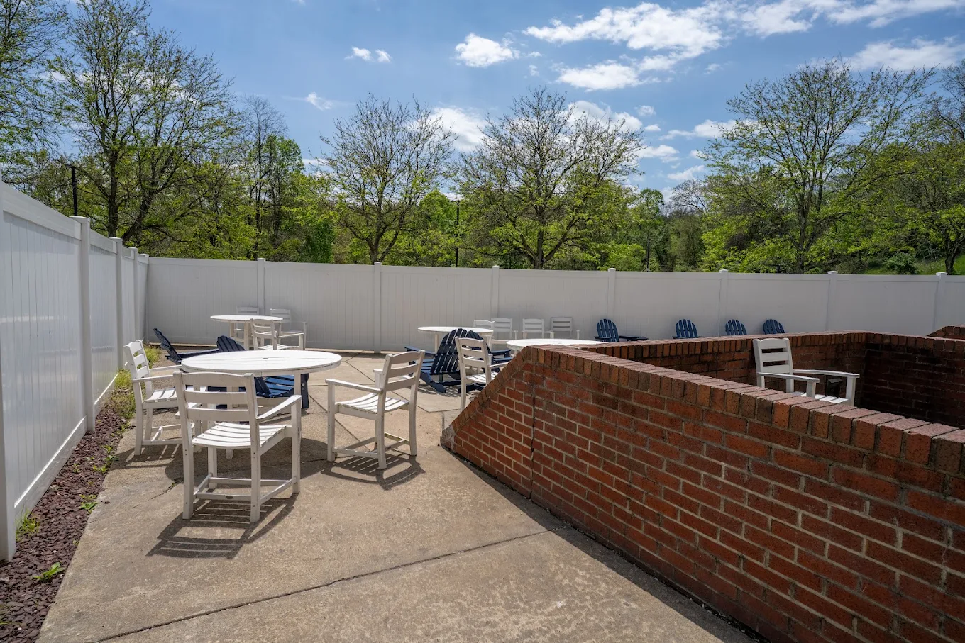 Outdoor patio with tables, chairs, and surrounding trees