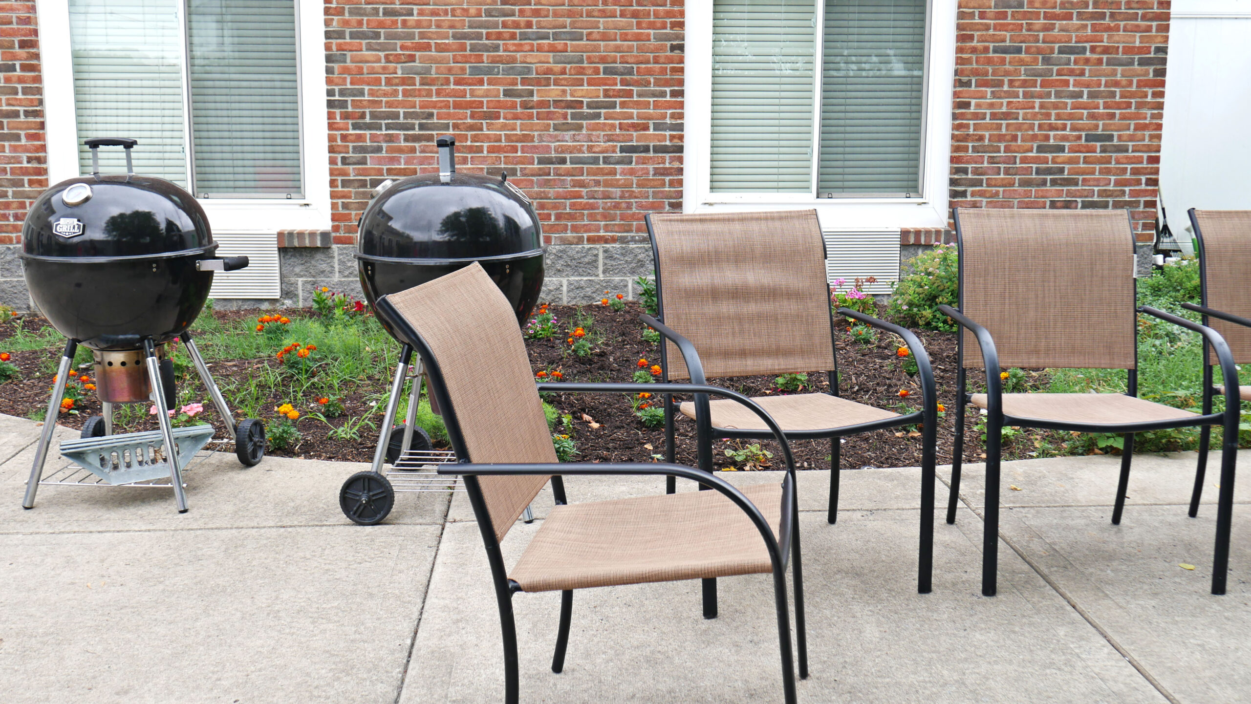 Grill stations and chairs beside landscaped flower beds