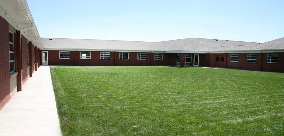Large courtyard with grass and surrounding brick buildings