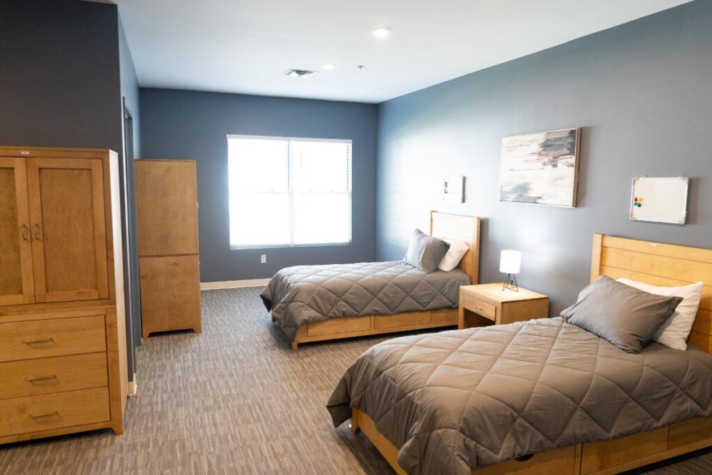 Bright bedroom with two single beds, wood furniture, and a large window