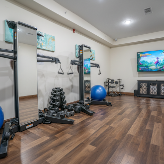 Indoor gym with weights, mirrors, and fitness machines.