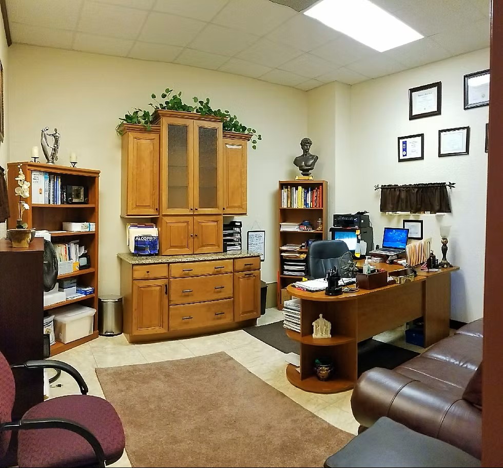 Sleek white-fronted desk with black chair and kitchenette