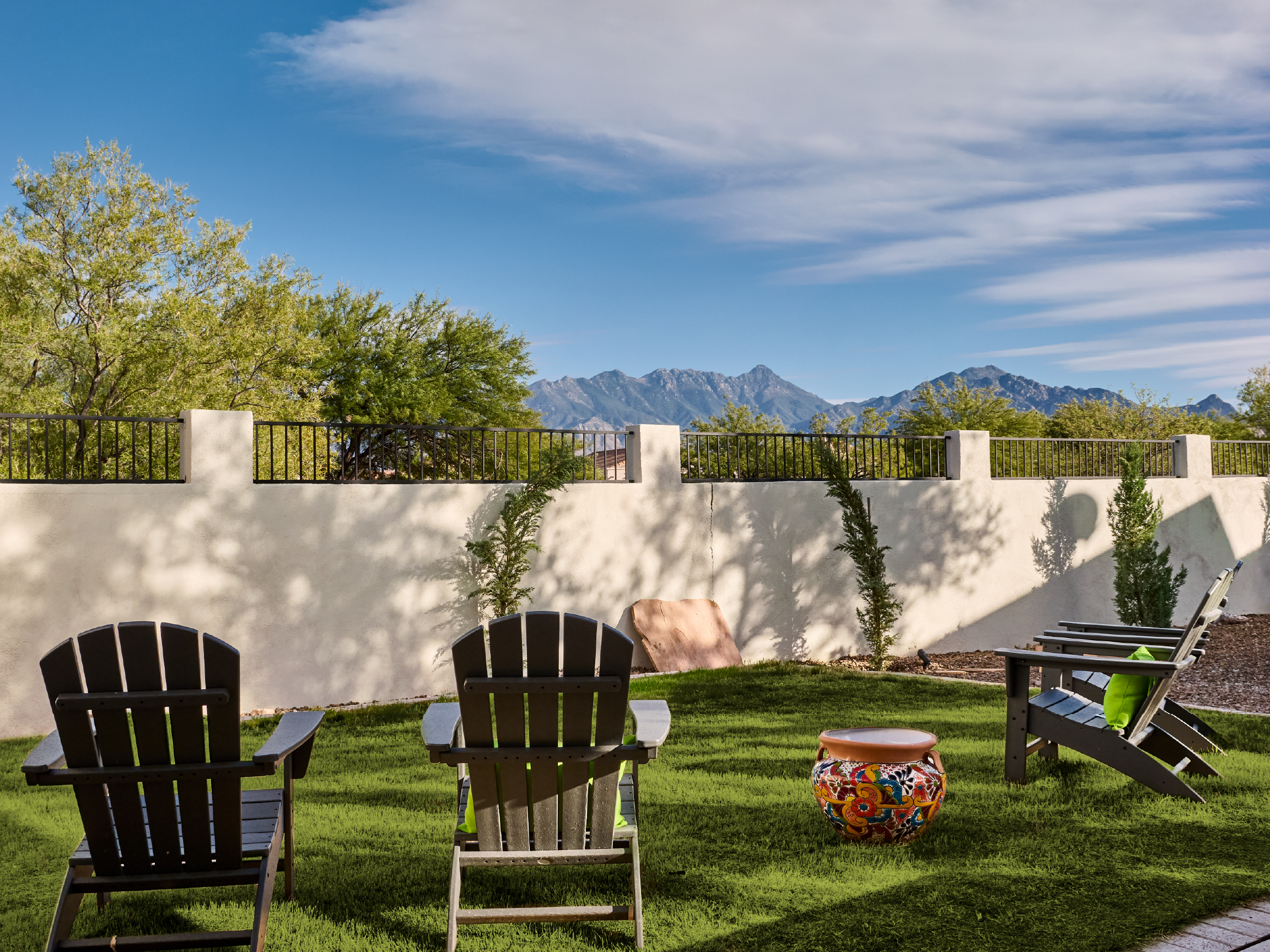 Outdoor chairs on grass facing mountain views and blue sky.