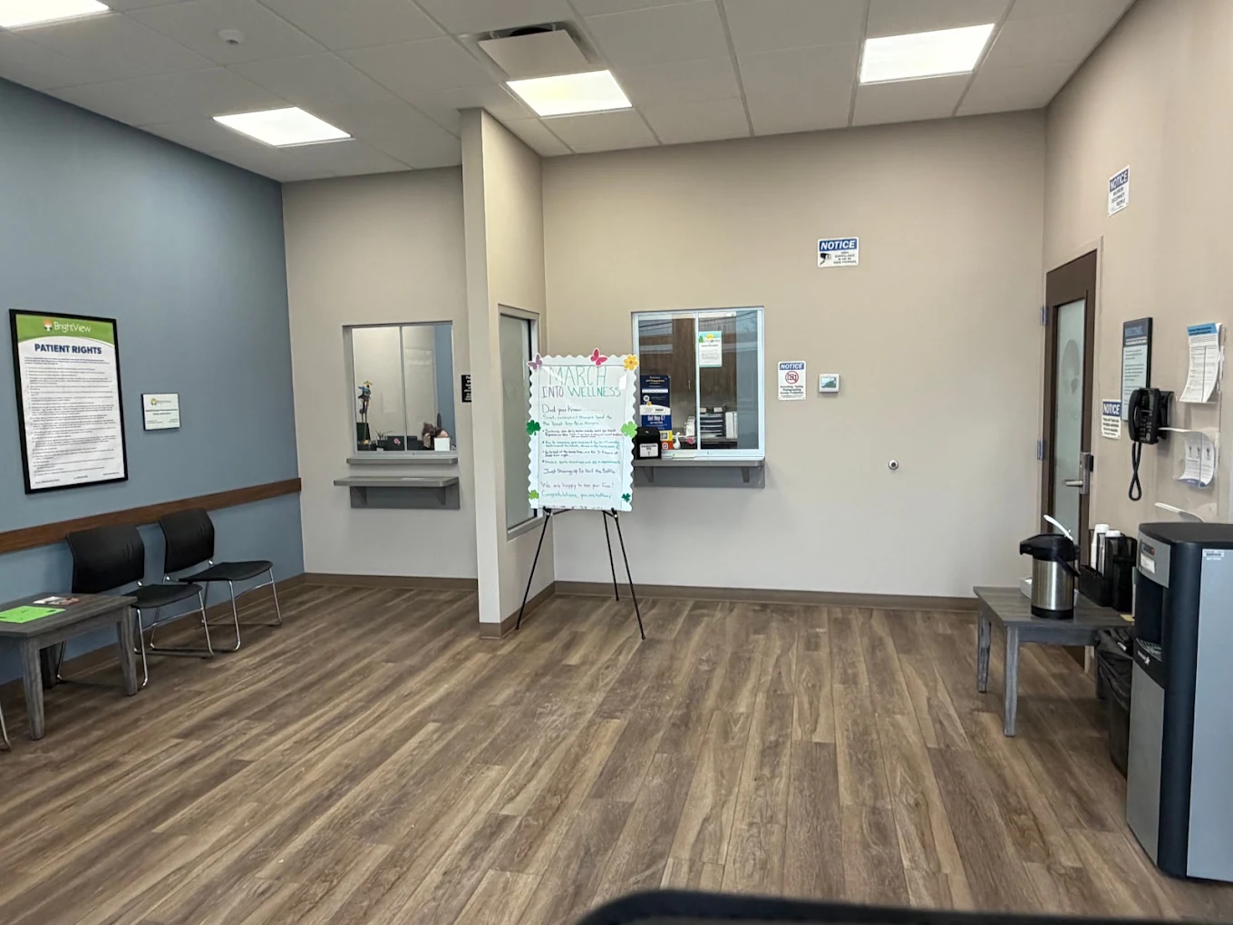 BrightView Health check-in area with service windows, patient seating, informational display, beverage station, and wood-look flooring