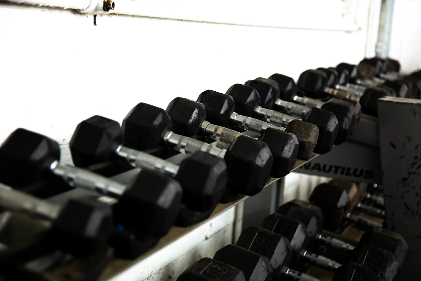 Rows of black hex dumbbells on metal rack