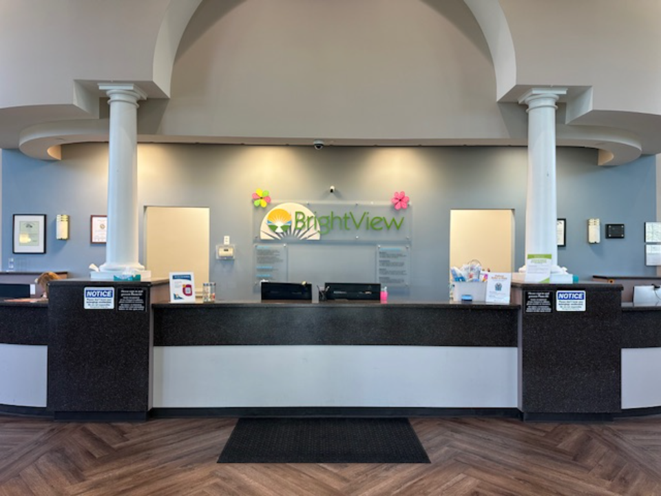 BrightView Health reception desk beneath an arched entryway with BrightView logo displayed on the blue wall behind the counter