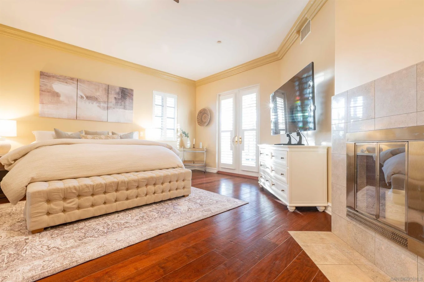 Bright bedroom with king bed, TV, and fireplace