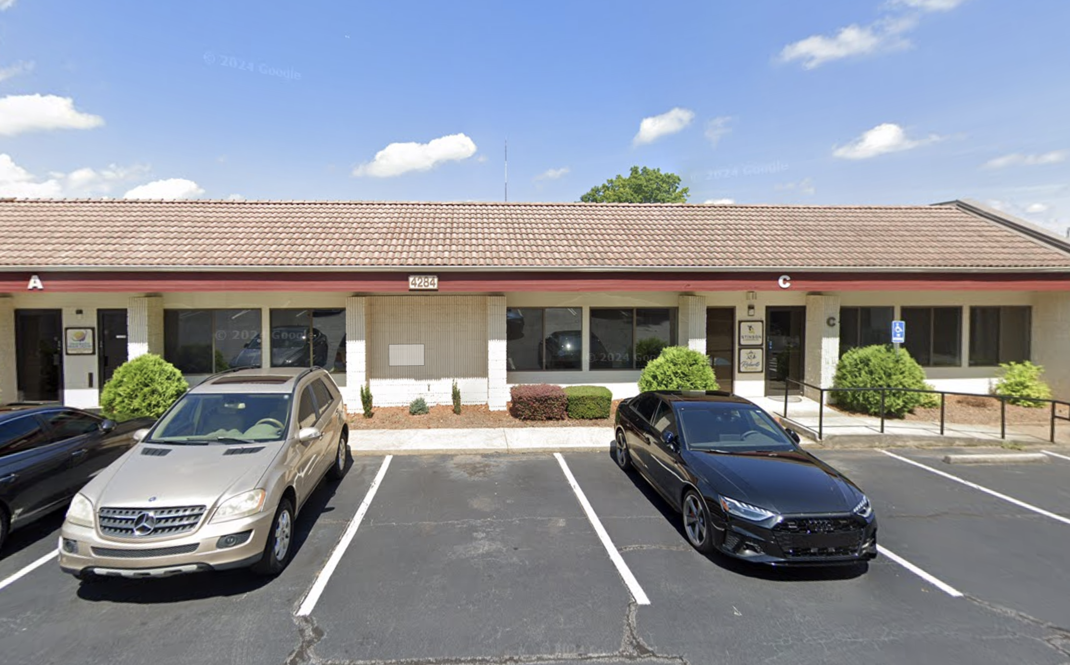 Single-story commercial building with parking lot and entrance ramp