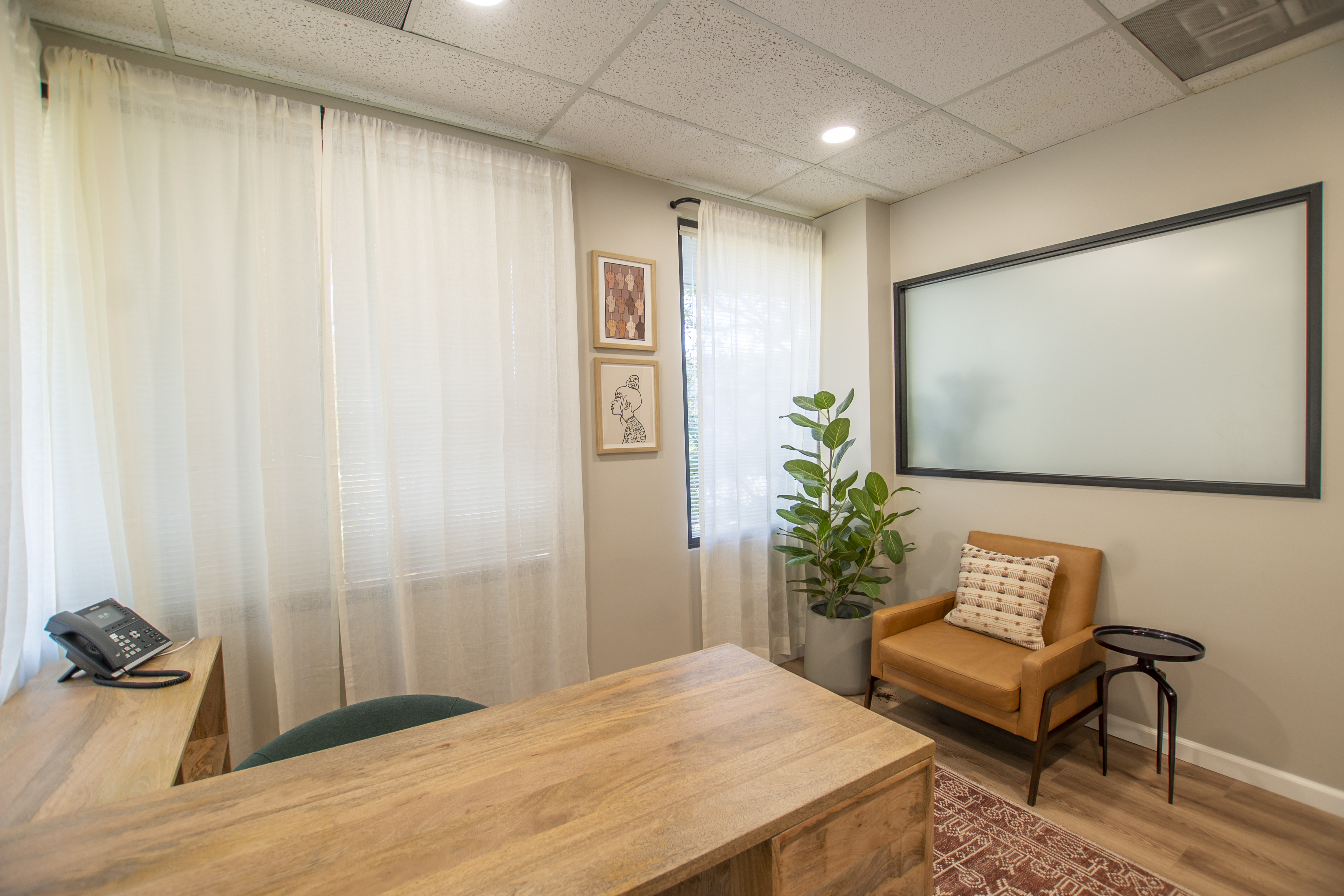 Private office with wood desk, chair, and plant