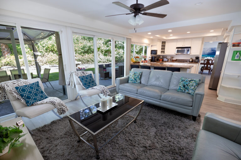 Lounge with sofas and open layout leading to kitchen and patio