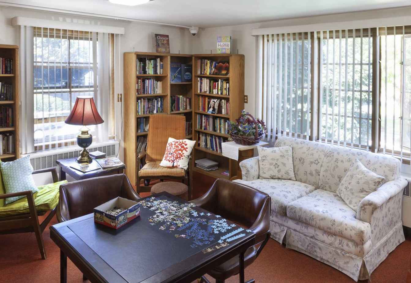Cozy room with bookshelves, puzzle table, and soft seating