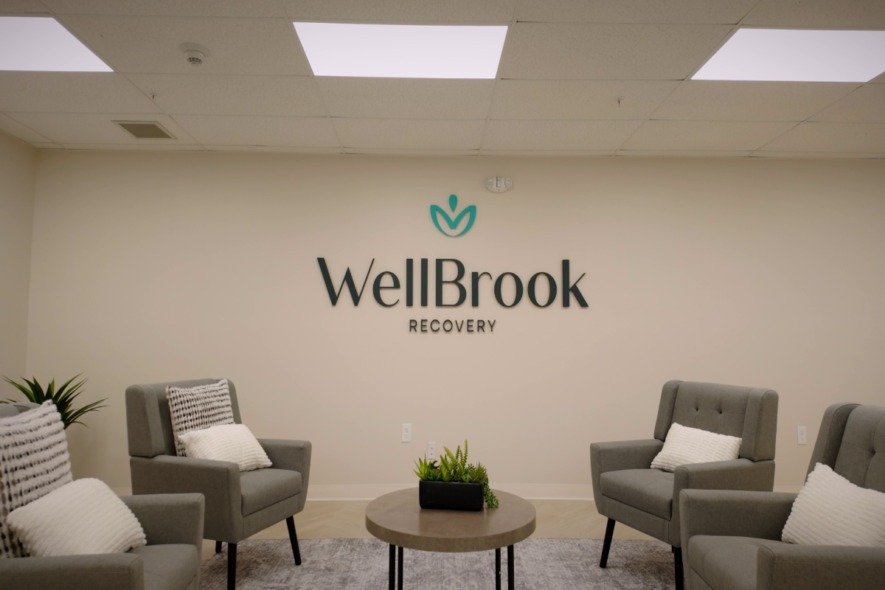 Waiting area with lounge chairs and WellBrook Recovery logo