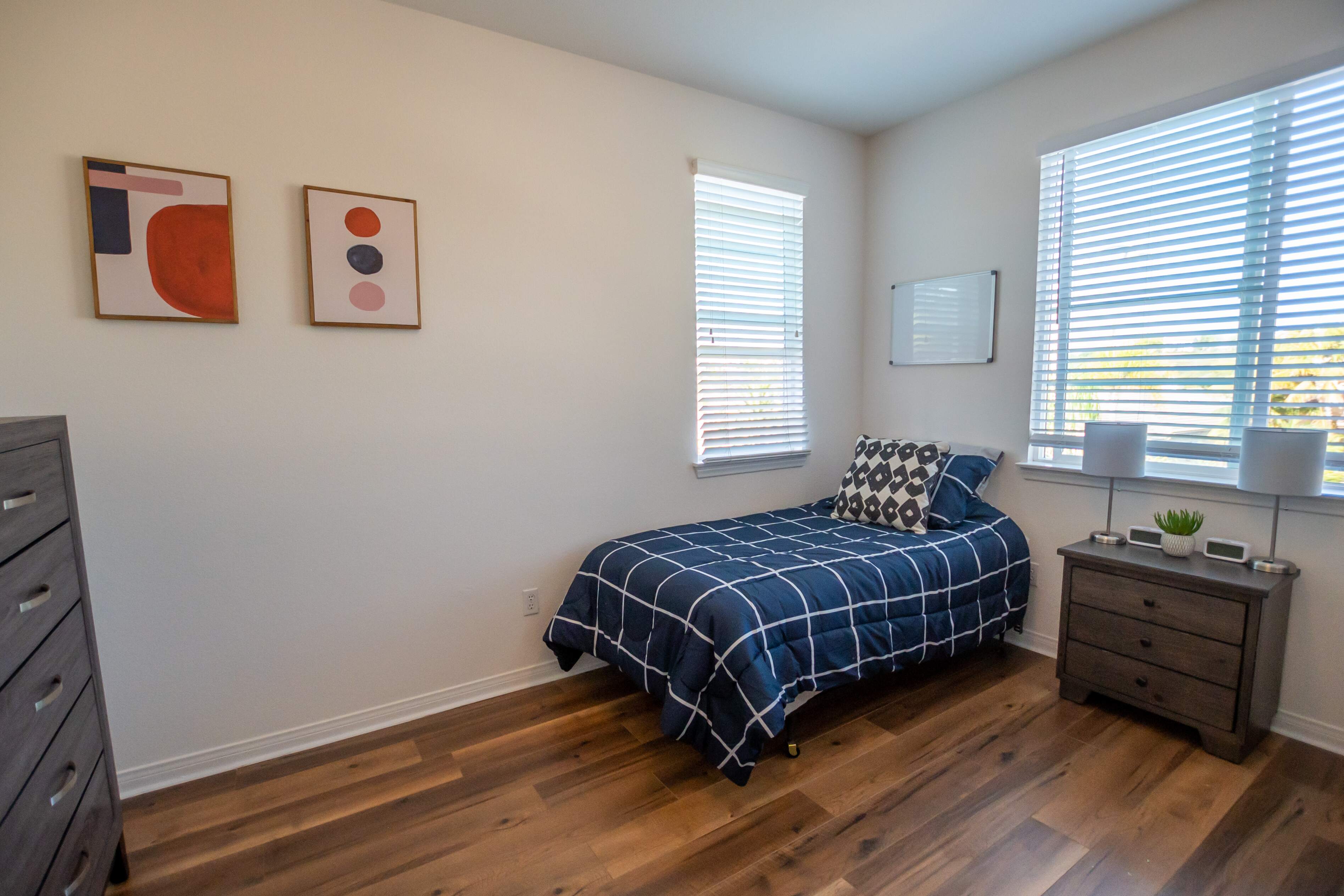 Single bed with navy plaid bedding and window views