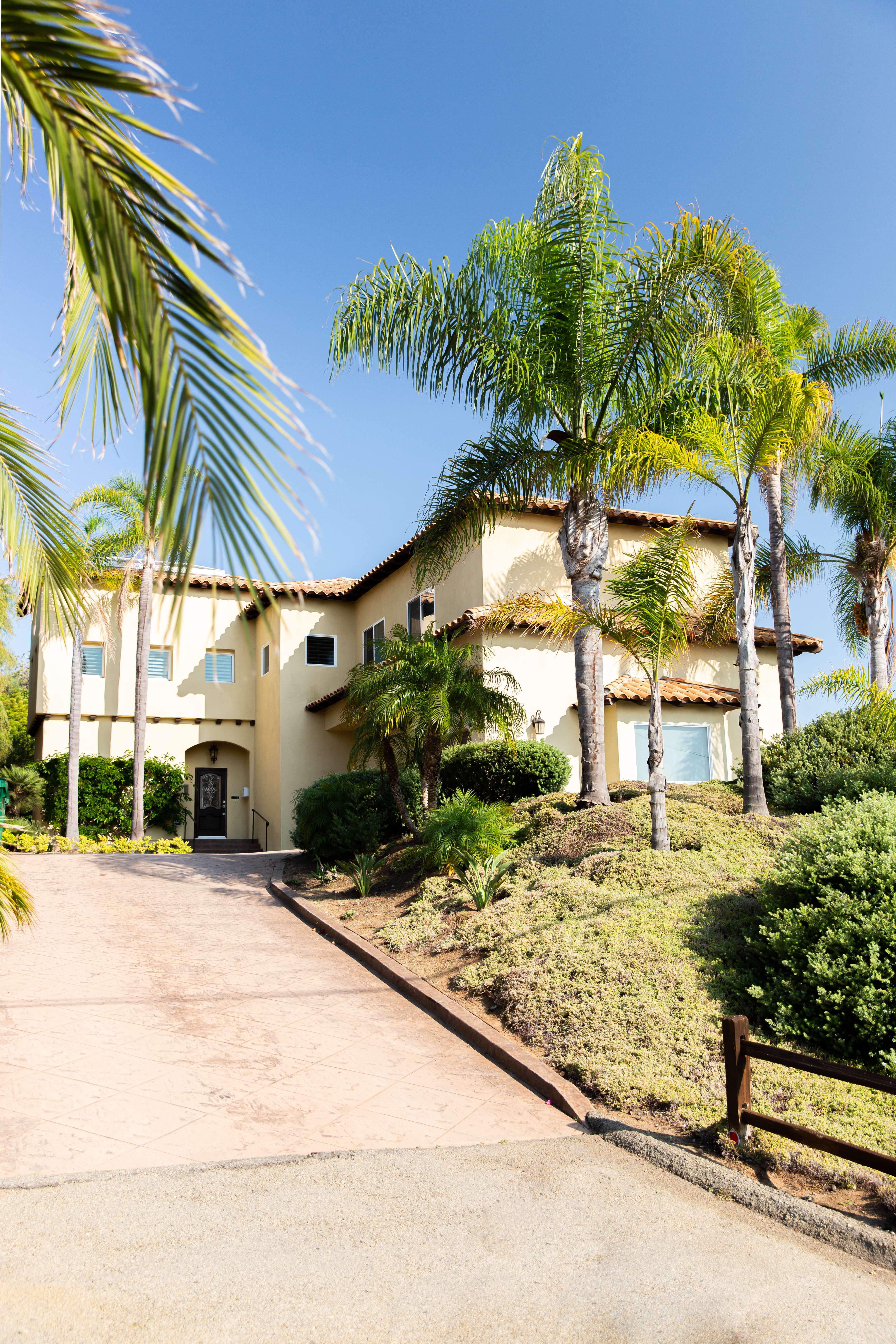 Palm-lined driveway leading to yellow stucco house