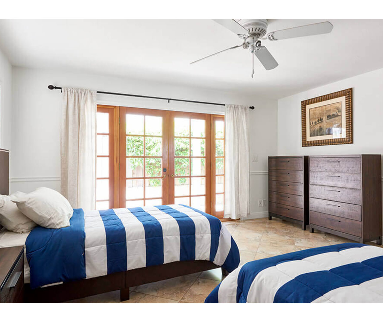 A bedroom with two twin beds, a dresser, and glass doors leading outside.