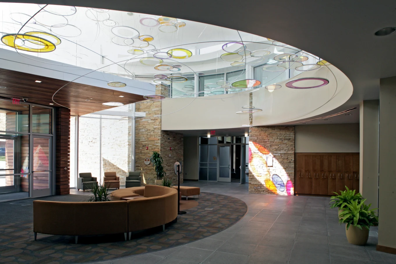 Curved lobby seating beneath colorful hanging ceiling art