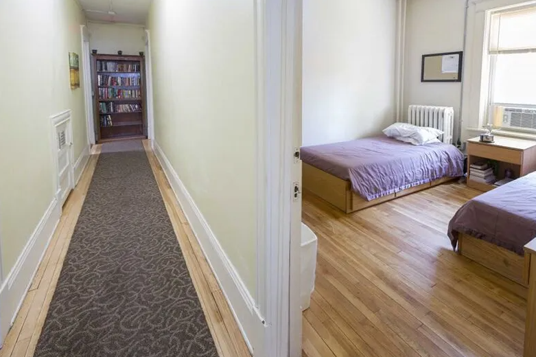 Hallway leading to a shared bedroom with twin beds and hardwood floors