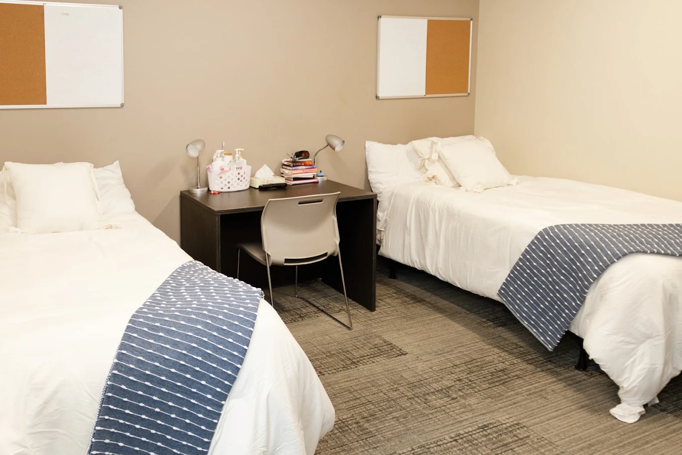 Shared bedroom with three beds, desks, and neutral decor