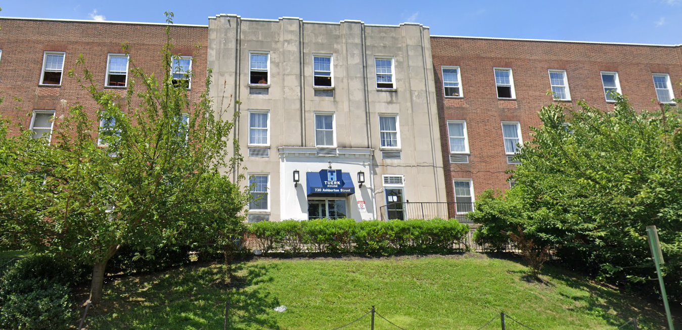 Exterior of Tuerk House with blue awning and trees in front