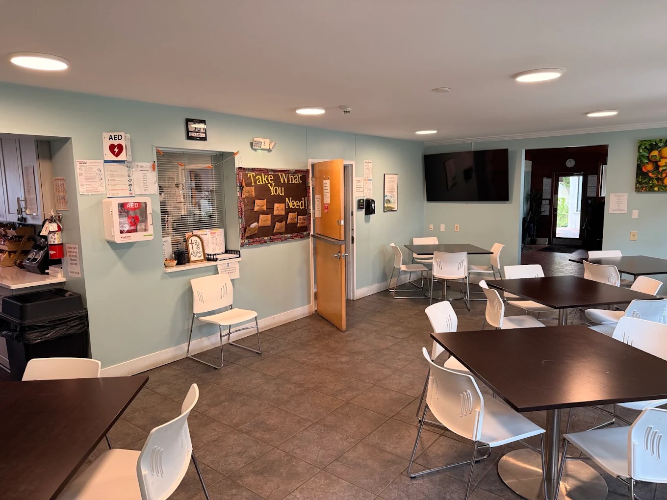 Dining area with tables, white chairs, and wall-mounted TV