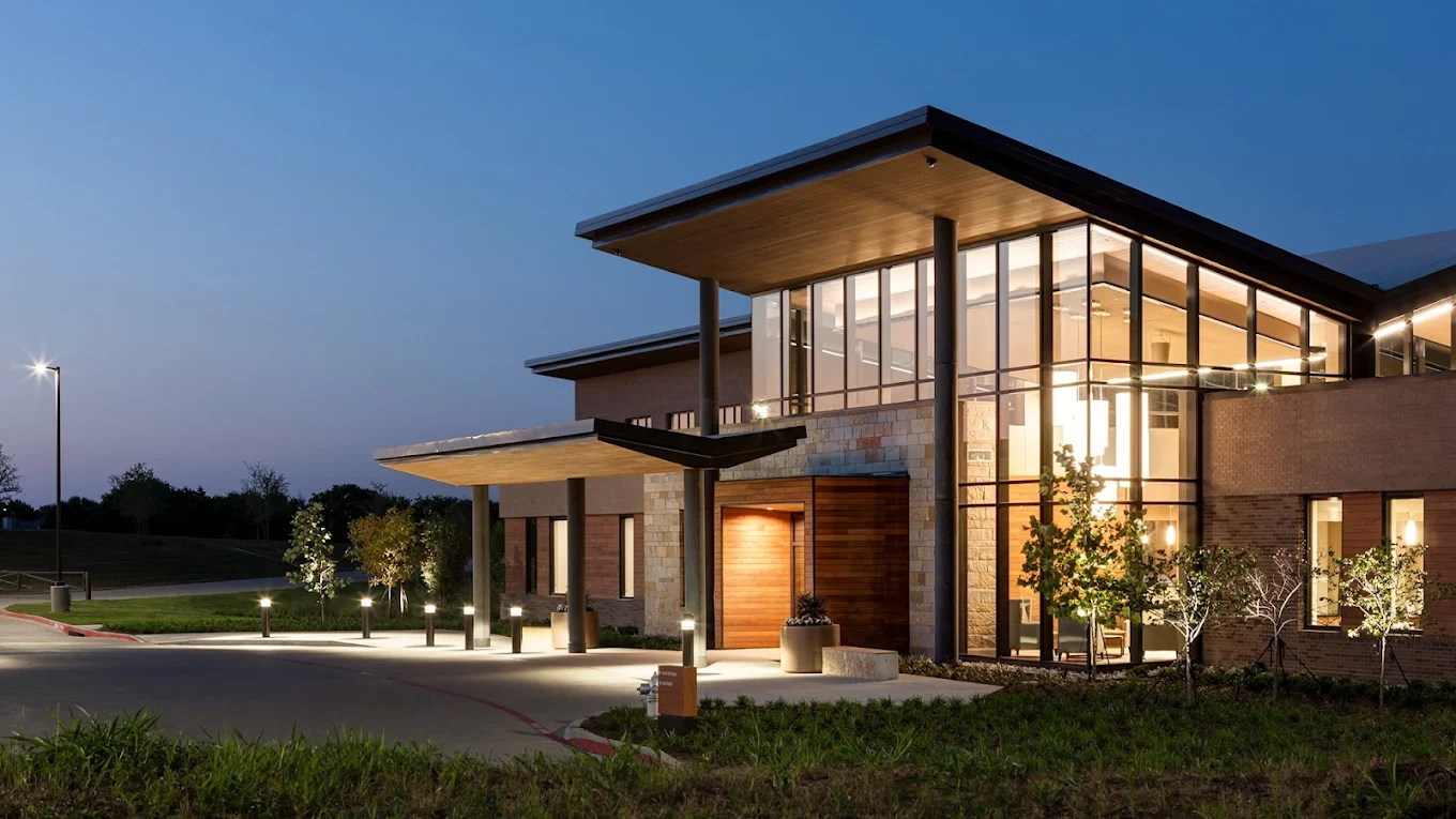 Modern rehab center exterior with glass facade at dusk