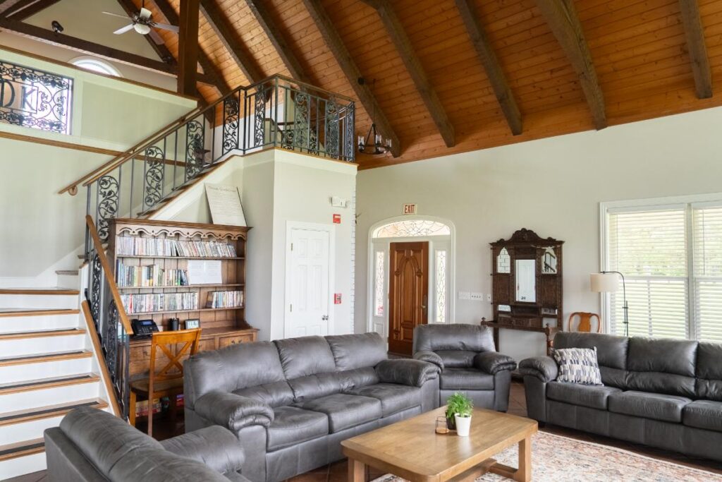 Cozy living room with gray sofas, vaulted wood ceiling, and a staircase with ornate railing