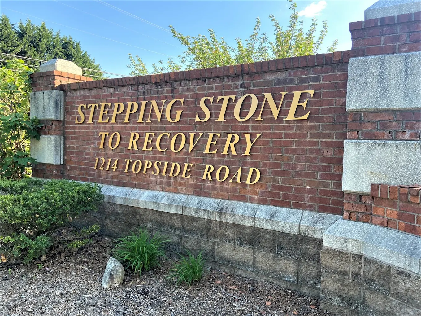 Brick Stepping Stone to Recovery sign beside landscaping