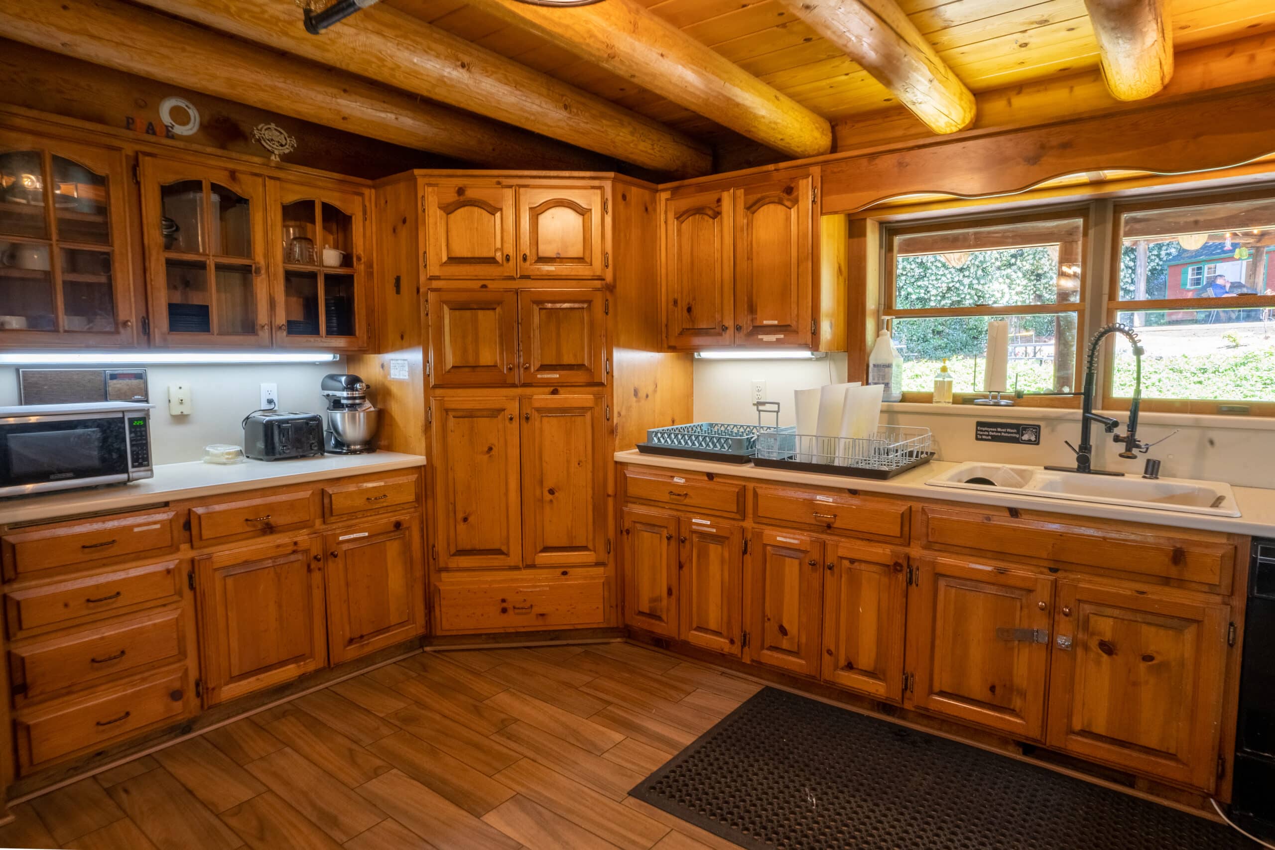 Rustic-style kitchen with wooden cabinets, modern appliances, and window views of greenery outside