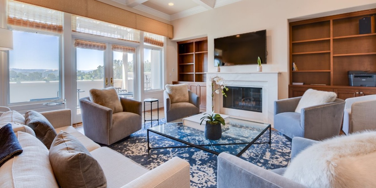 Modern living room with armchairs, fireplace, and large windows.