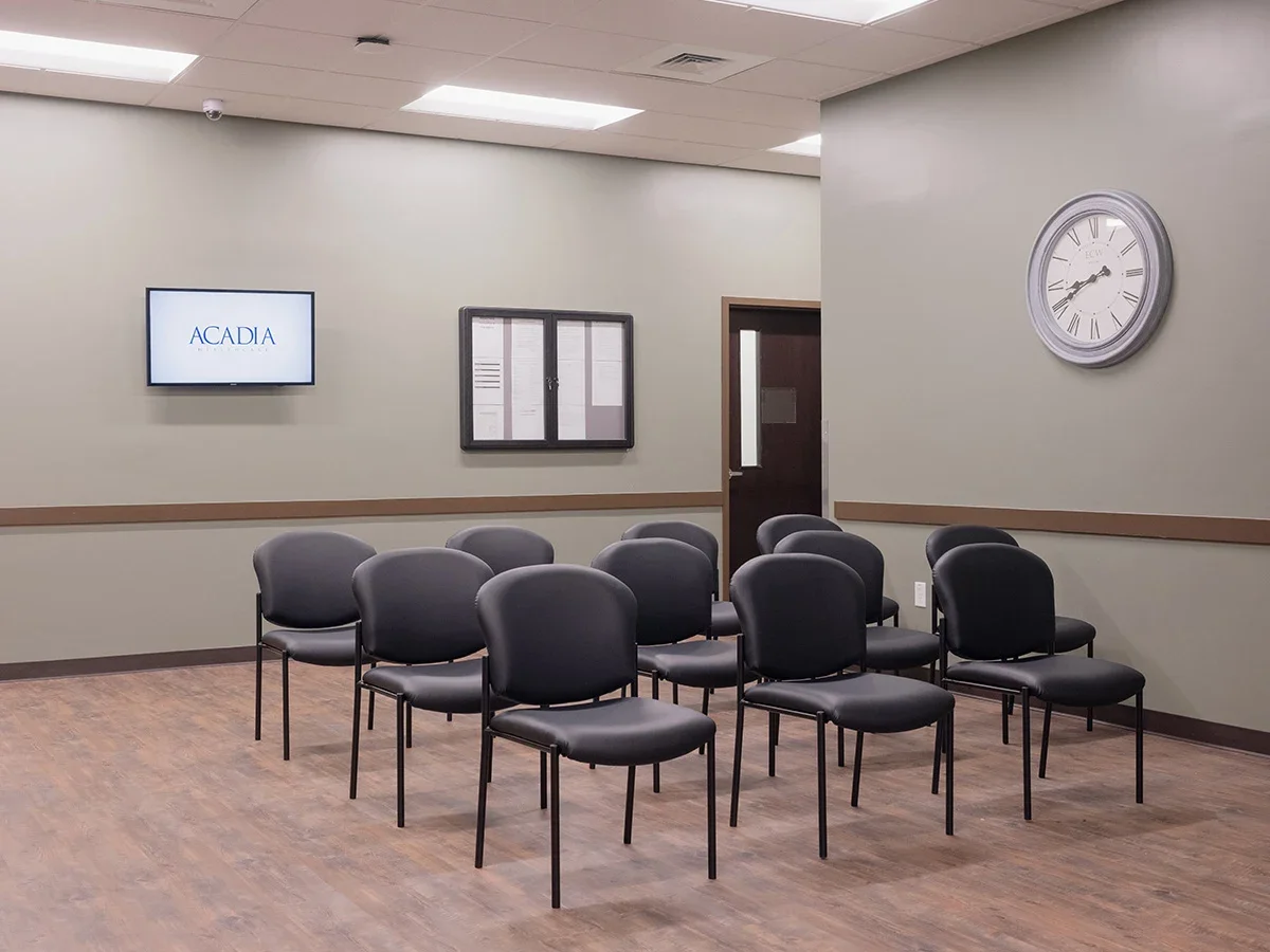 Chairs arranged in rows for group sessions with wall-mounted screen and clock
