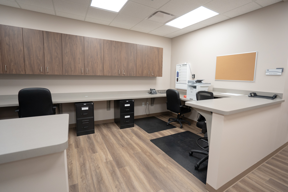 Nurses station with work counters, cabinets, and office chairs