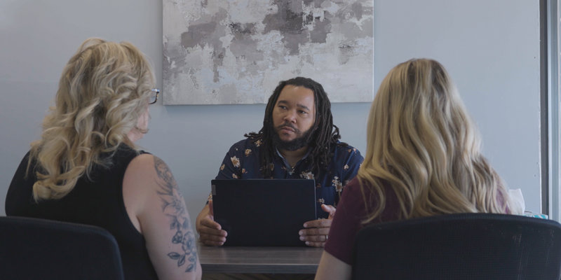 A therapist attentively listens to two clients during a session, fostering a supportive and open atmosphere for discussion.