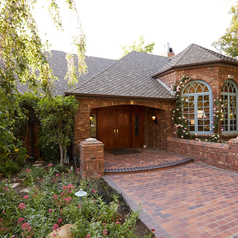 Brick facility entrance with garden and arched windows