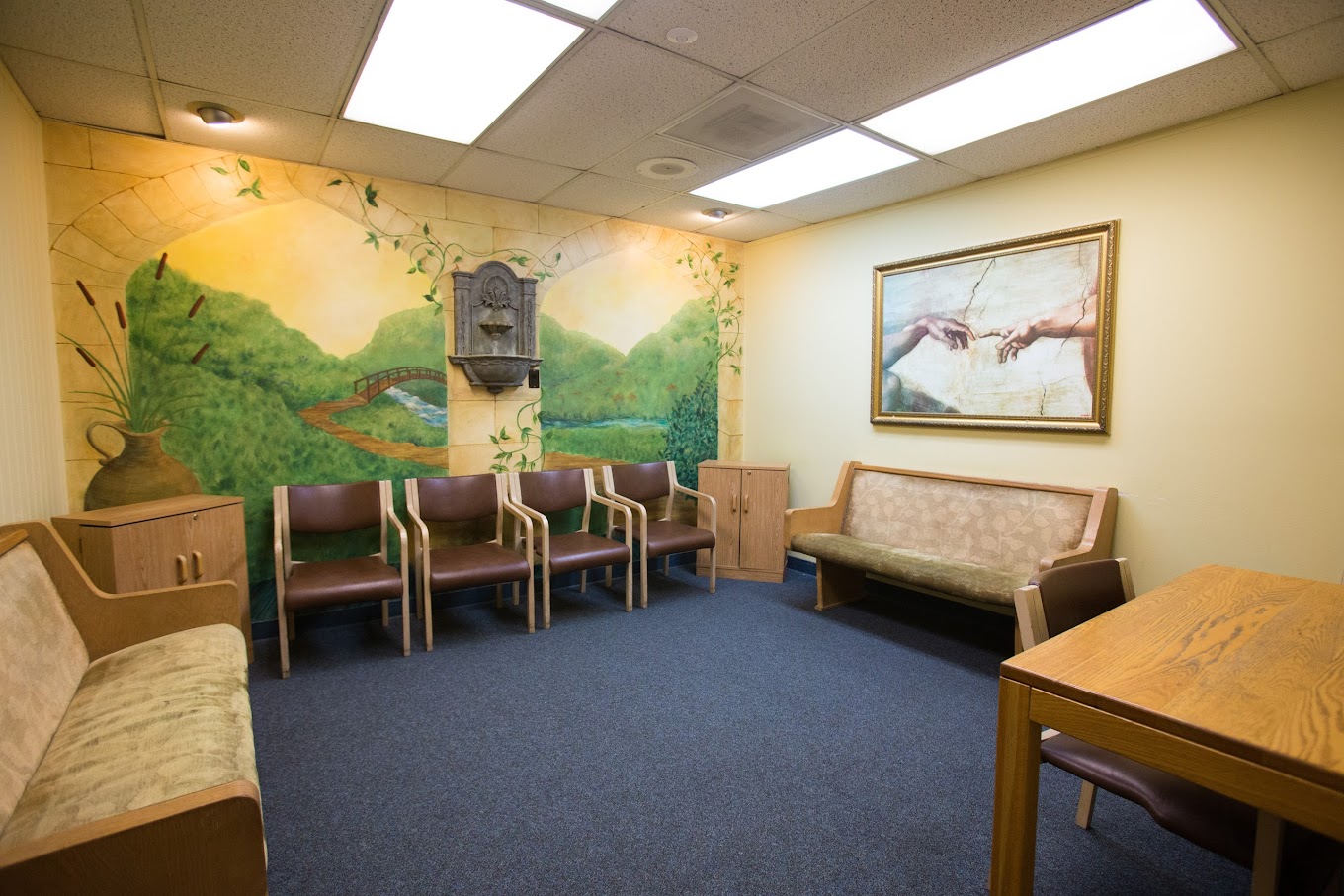  A cozy and inviting room with comfortable seating, warm lighting, and a serene mural, creating a peaceful and relaxing environment.
