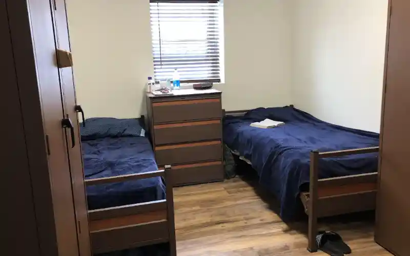 Shared bedroom with two single beds and simple furnishings.