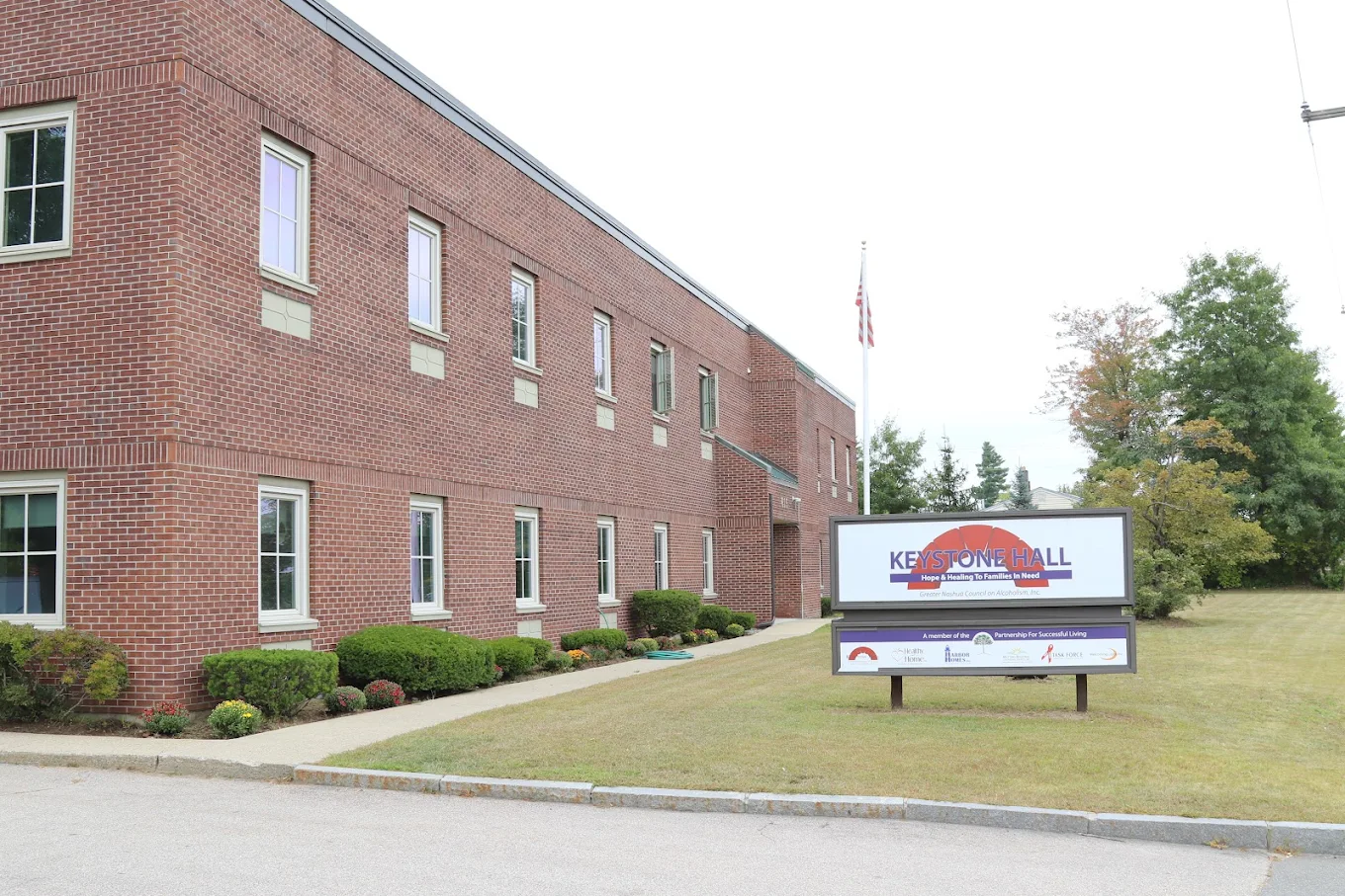 Brick Keystone Hall building with facility sign and lawn