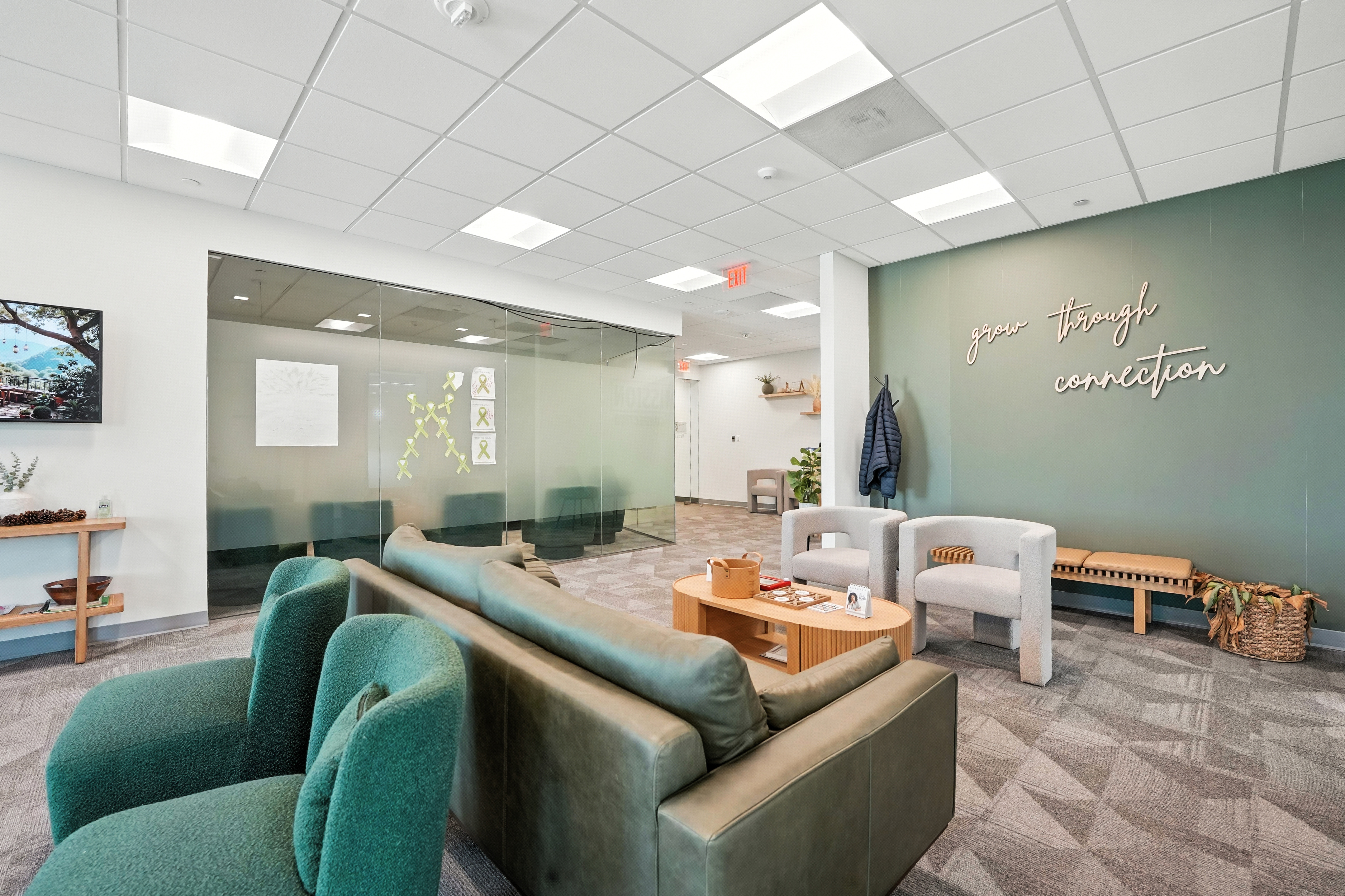 Modern lounge with green sofa and wall reading “grow through connection”
