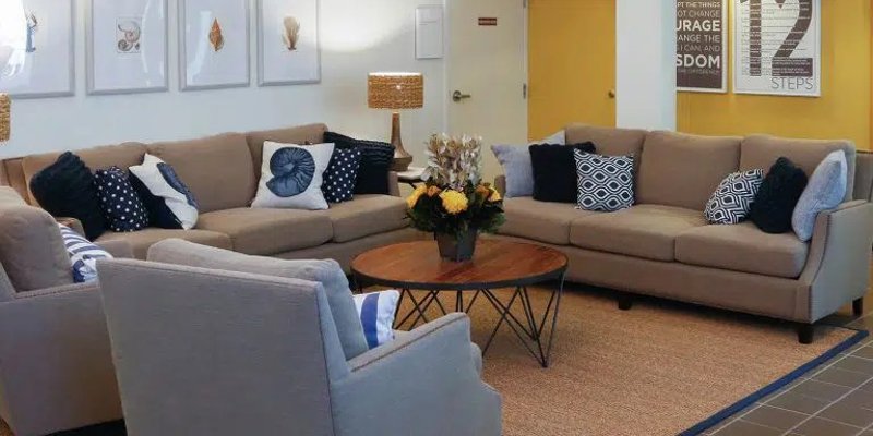 A comfortable lounge featuring plush beige sofas, stylish cushions, and a wooden coffee table. Soft lighting and modern décor create a relaxing space.