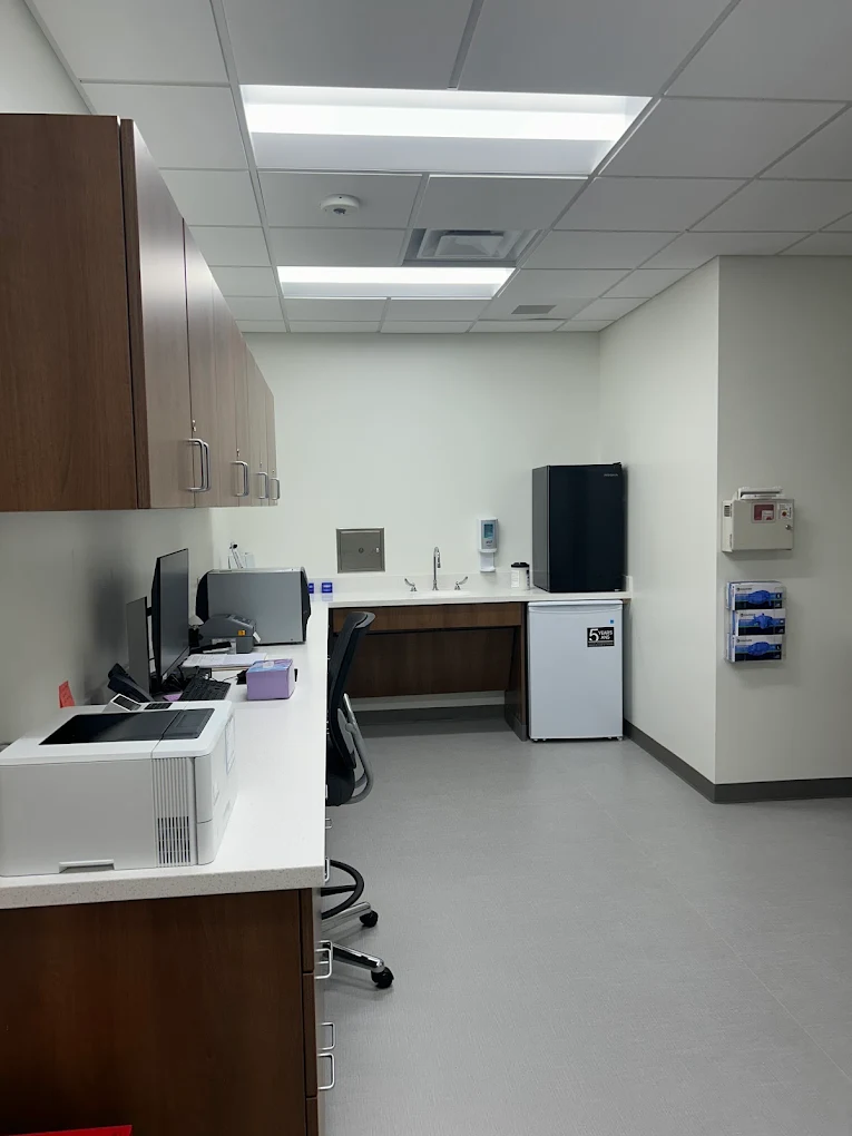 Clinical workspace with cabinets, computers, and medical supplies